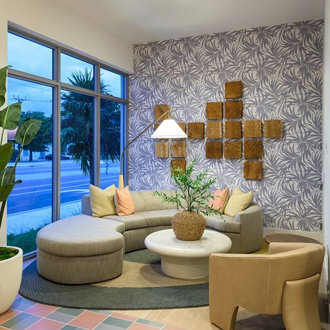 A living room with a grey couch and a wall with a pattern.